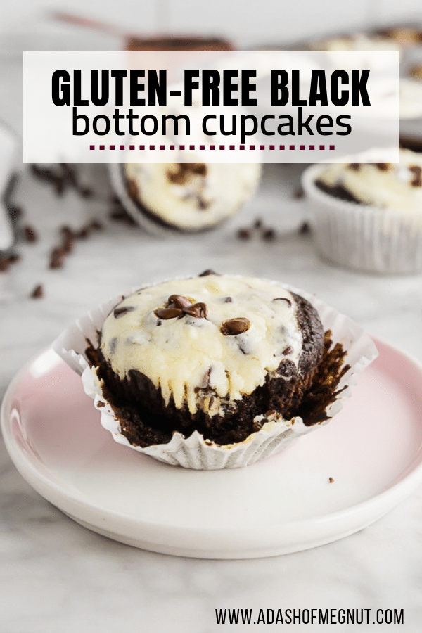 A photo of a gluten-free black bottom cupcake with cheesecake filling and topped with mini chocolate chips with the muffin liner unwrapped on a marble table.