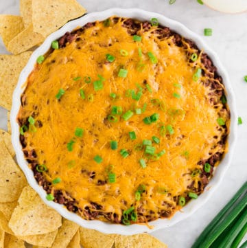 A photo of a tart pan filled with chili cheese dip topped with green onions.