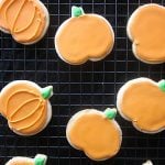 A photo of gluten free sugar cookies shaped like pumpkins on a baking sheet.