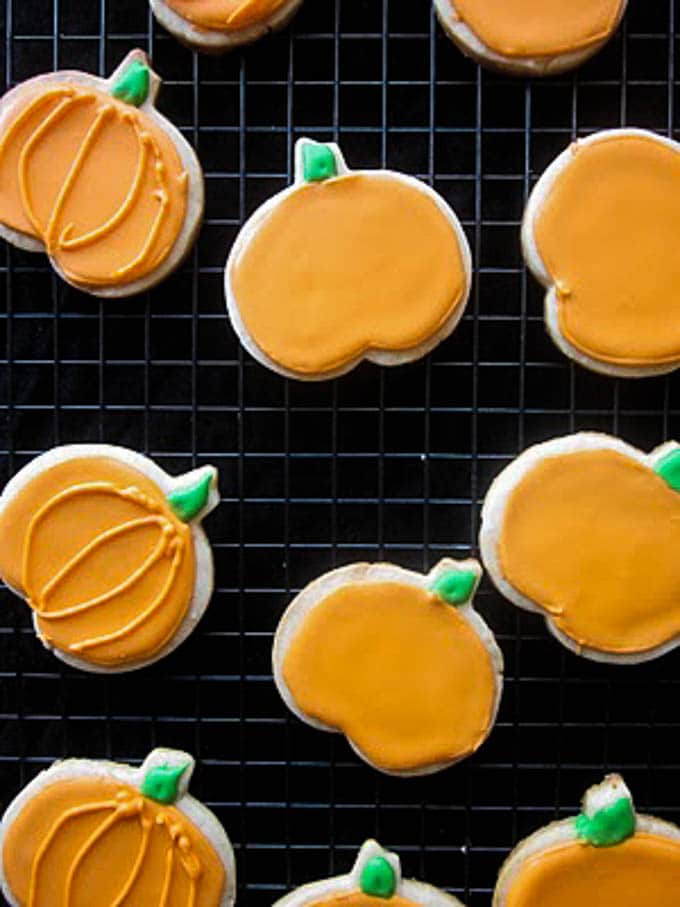 A photo of gluten free sugar cookies shaped like pumpkins on a baking sheet. 