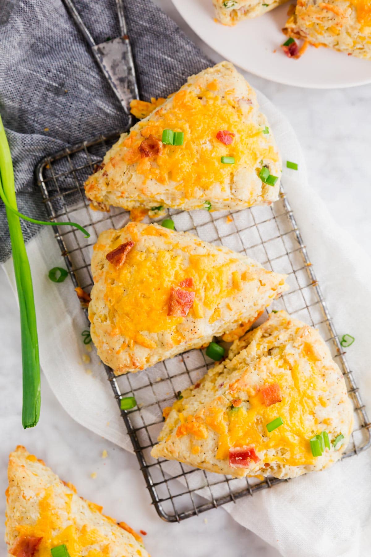 A cooling rack with three gluten-free bacon cheddar scones topped with green onions.