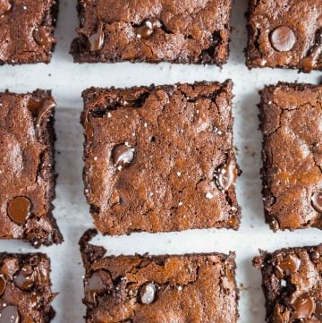 An overhead image showing a close up of 9 almond flour brownies sliced in squares topped with flaky salt.