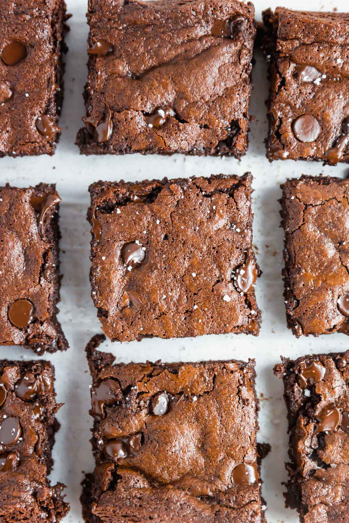 An overhead image showing a close up of 9 almond flour brownies sliced in squares topped with flaky salt.