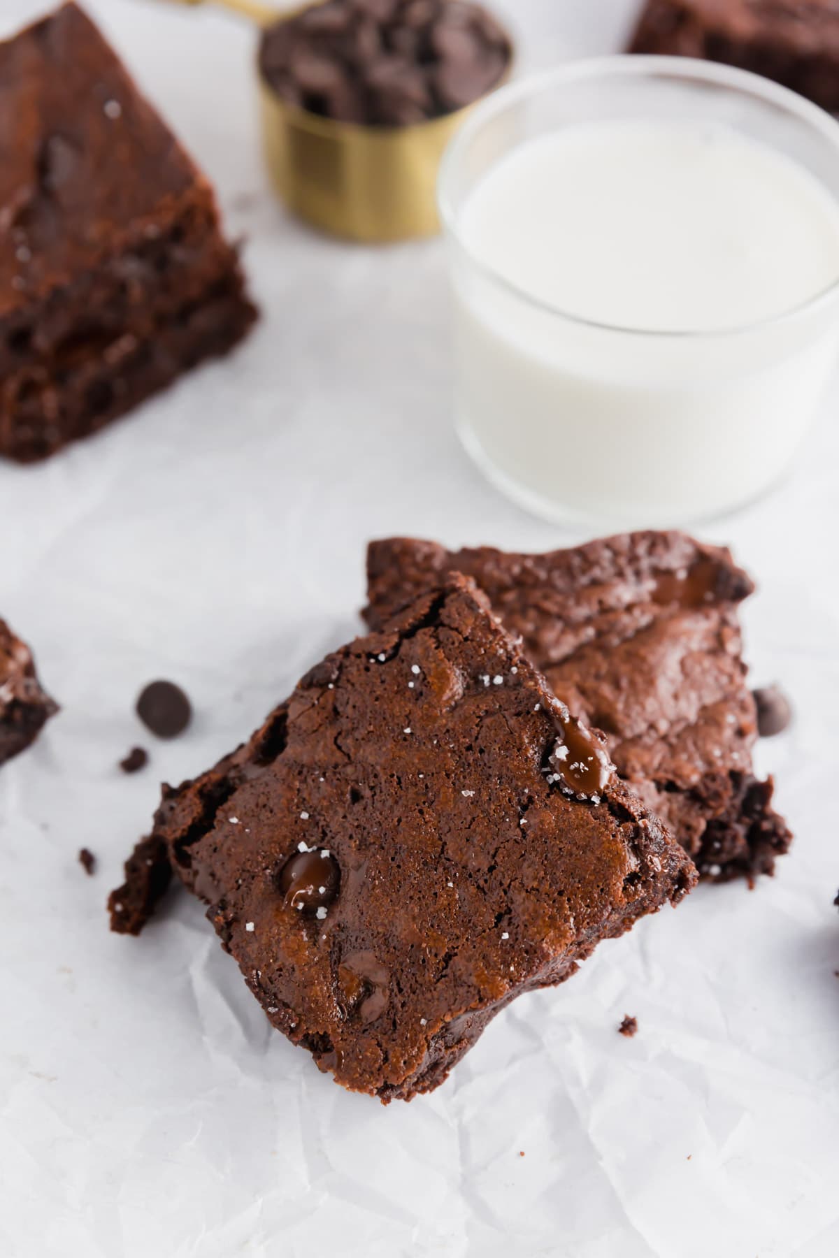 A photo showing two almond flour brownies stacked on top of each other with a glass of milk in the background.