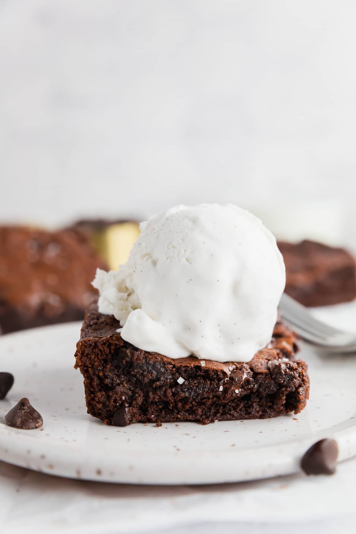 A straight on photo of a gluten-free almond flour brownie topped with a scoop of ice cream.