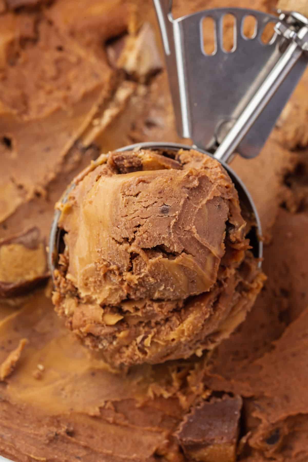 A scooper full of chocolate peanut butter ice cream in it.