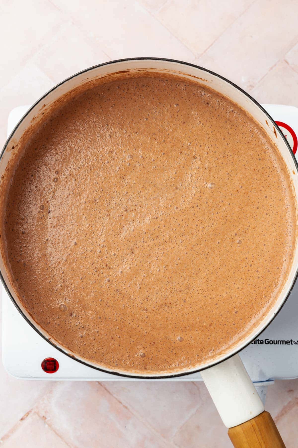 Chocolate custard in a white saucepan on an electric burner.