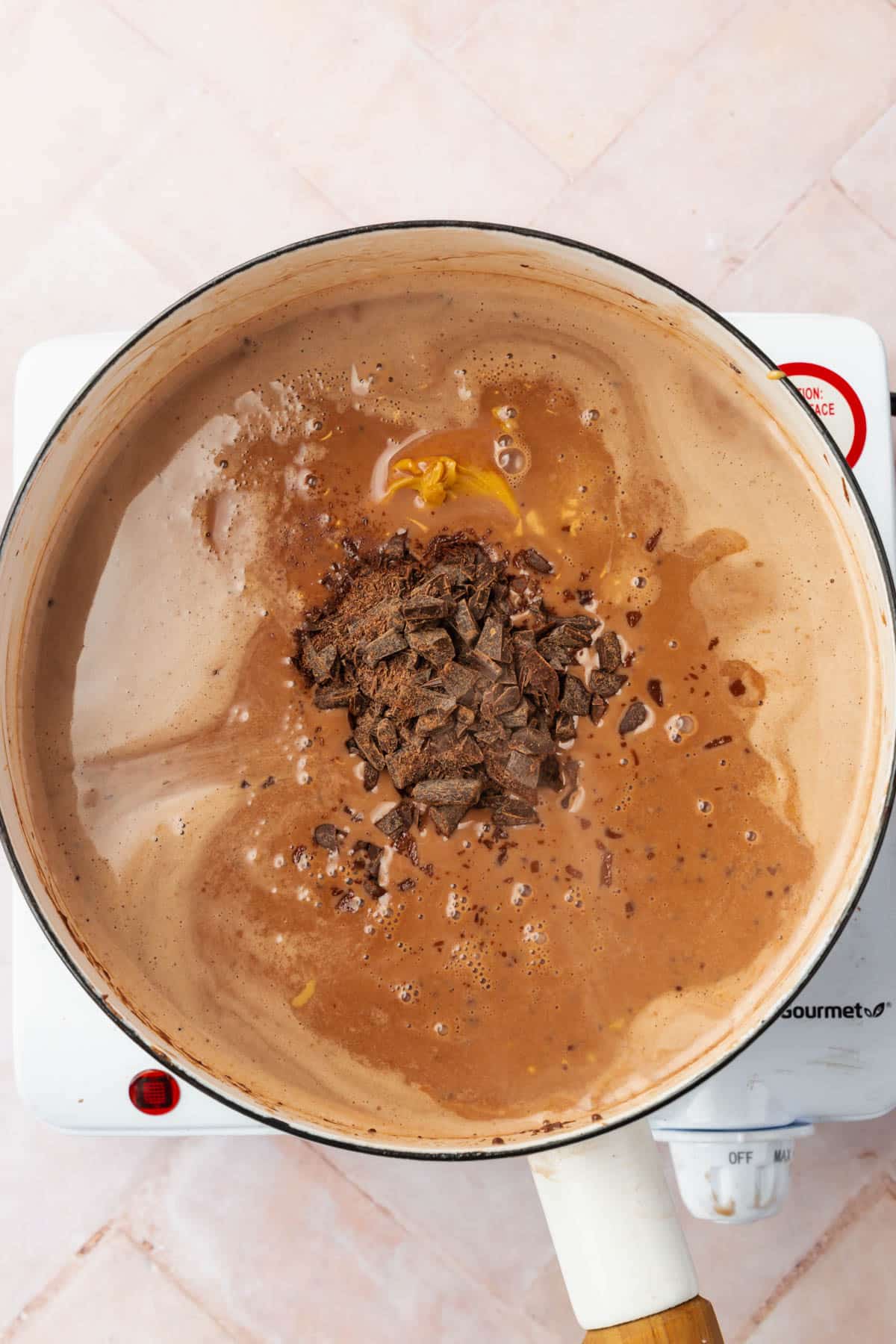 A white saucepan with chocolate custard, peanut butter, and chopped chocolate.