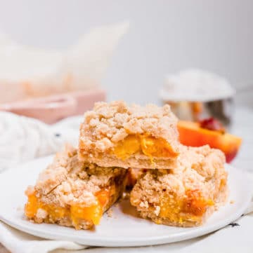 A view of three peach crumb bars in a stack on a plate.