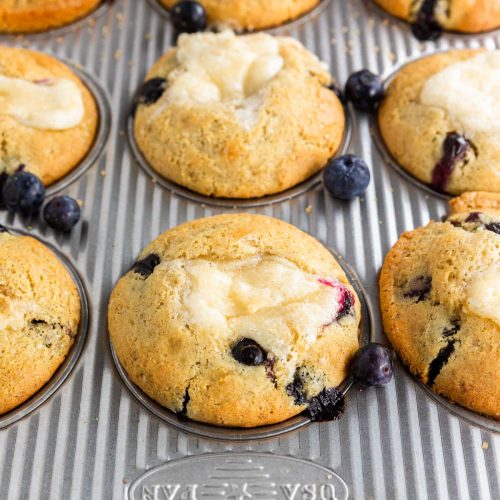 A photo of gluten-free blueberry cheesecake muffins in a muffin tin after baking.