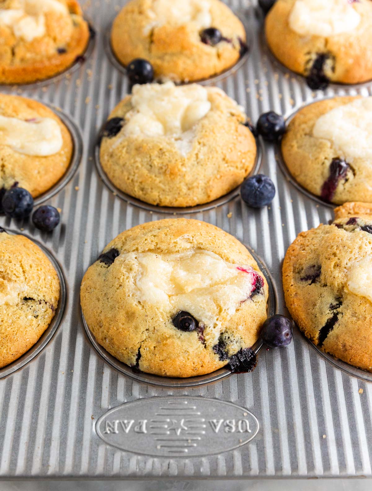 A photo of gluten-free blueberry cheesecake muffins in a muffin tin after baking. 