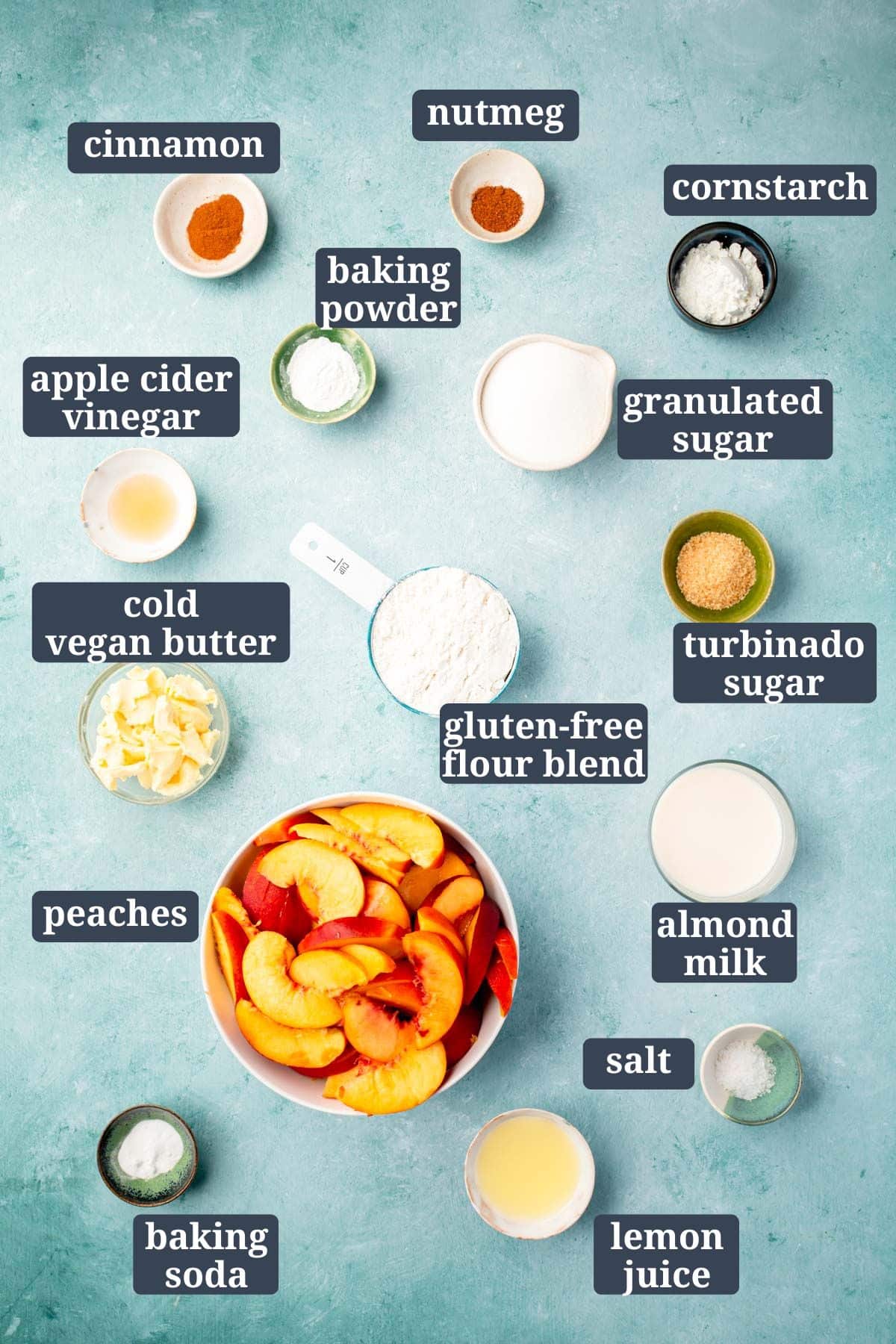 Small bowls of ingredients on a blue table for making gluten-free vegan peach cobbler with text overlay over each ingredient..