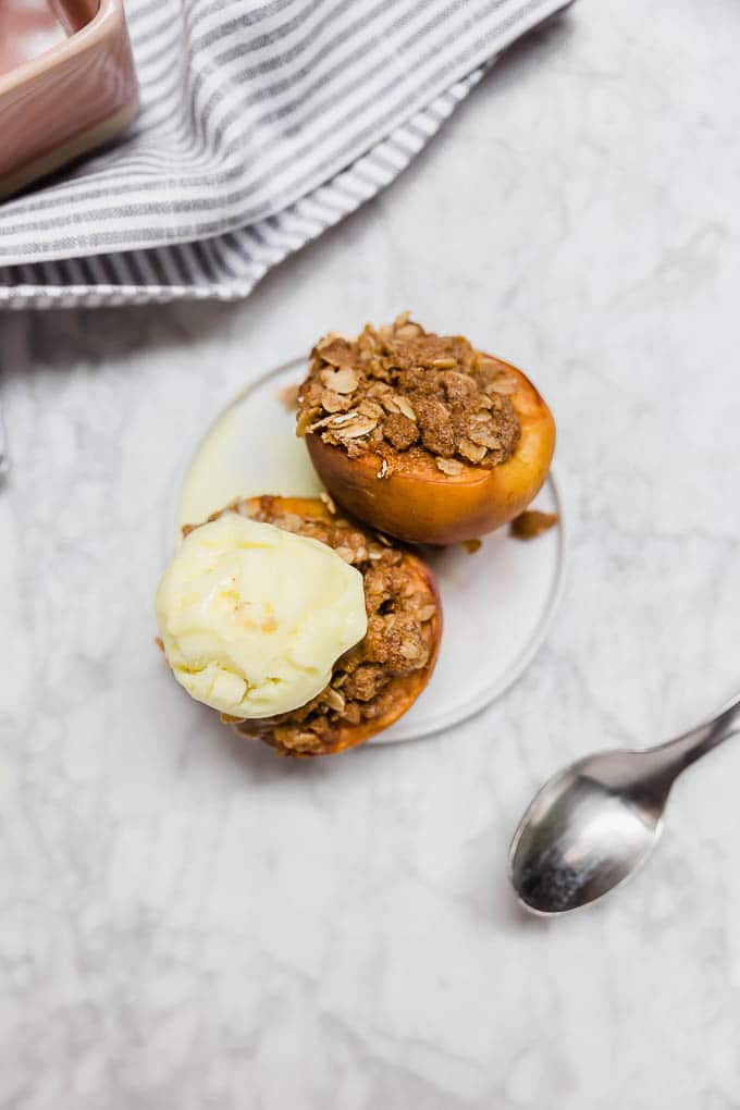 An aerial view of two halves of a peach stuffed with gluten-free streusel topping and a scoop of ice cream. 