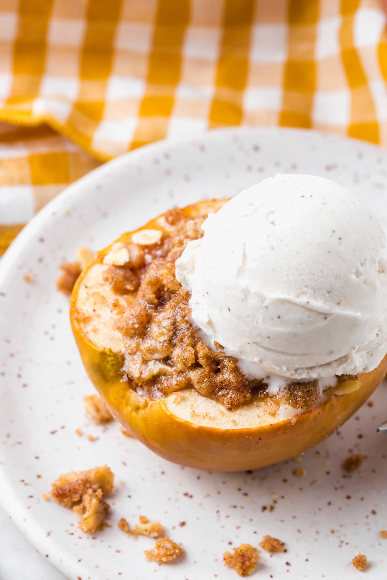 A photo of an apple stuffed with gluten-free streusel and topped with a scoop of ice cream.