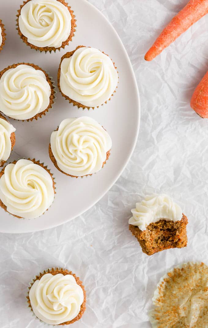 A platter of gluten free carrot cake cupcakes with cream cheese frosting.