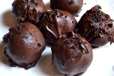 Chocolate oreo cheesecake truffles on a white plate.