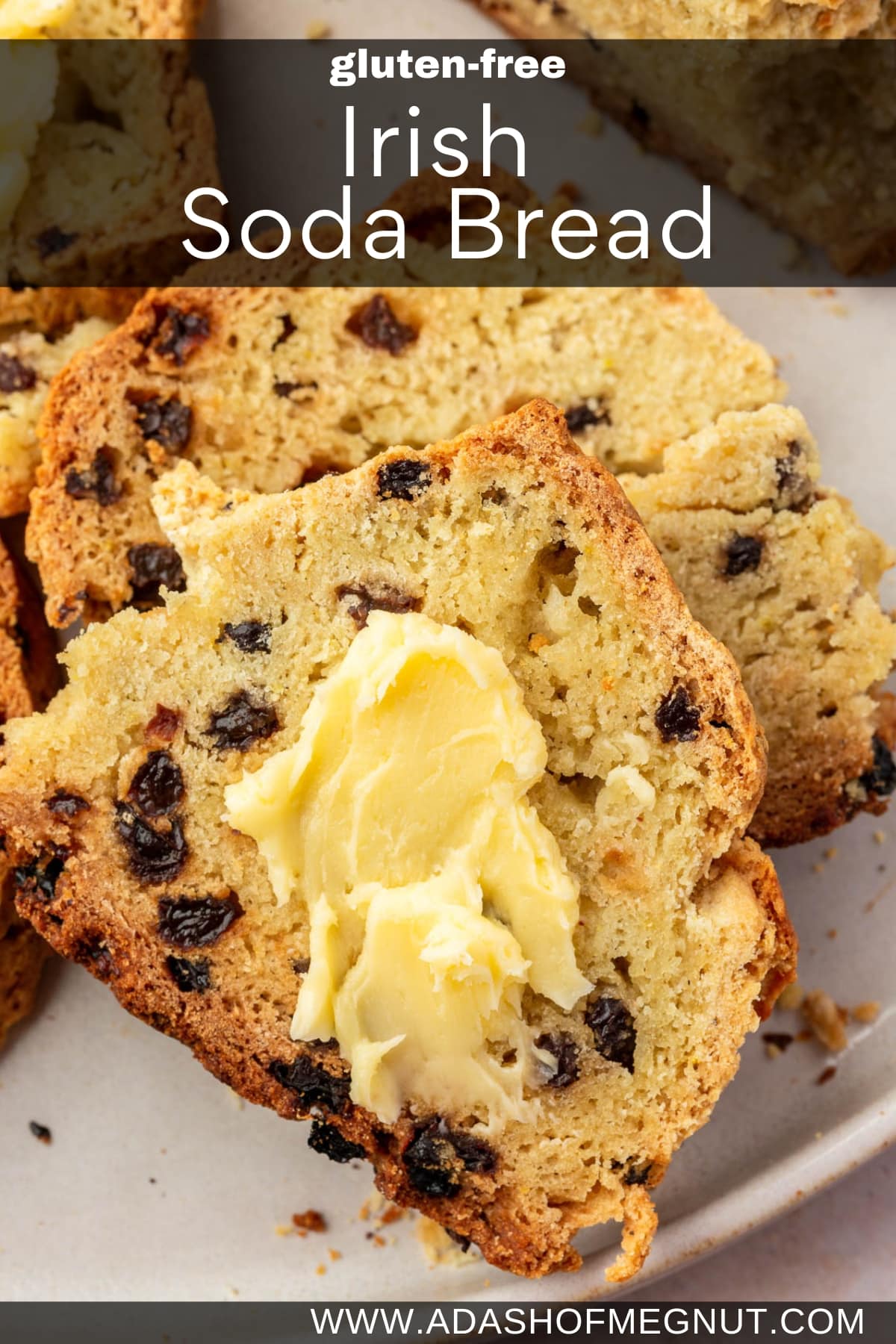 A photo of two slices of gluten-free Irish soda bread with currants topped with a slather of Irish butter with a loaf of Irish soda bread in the background.