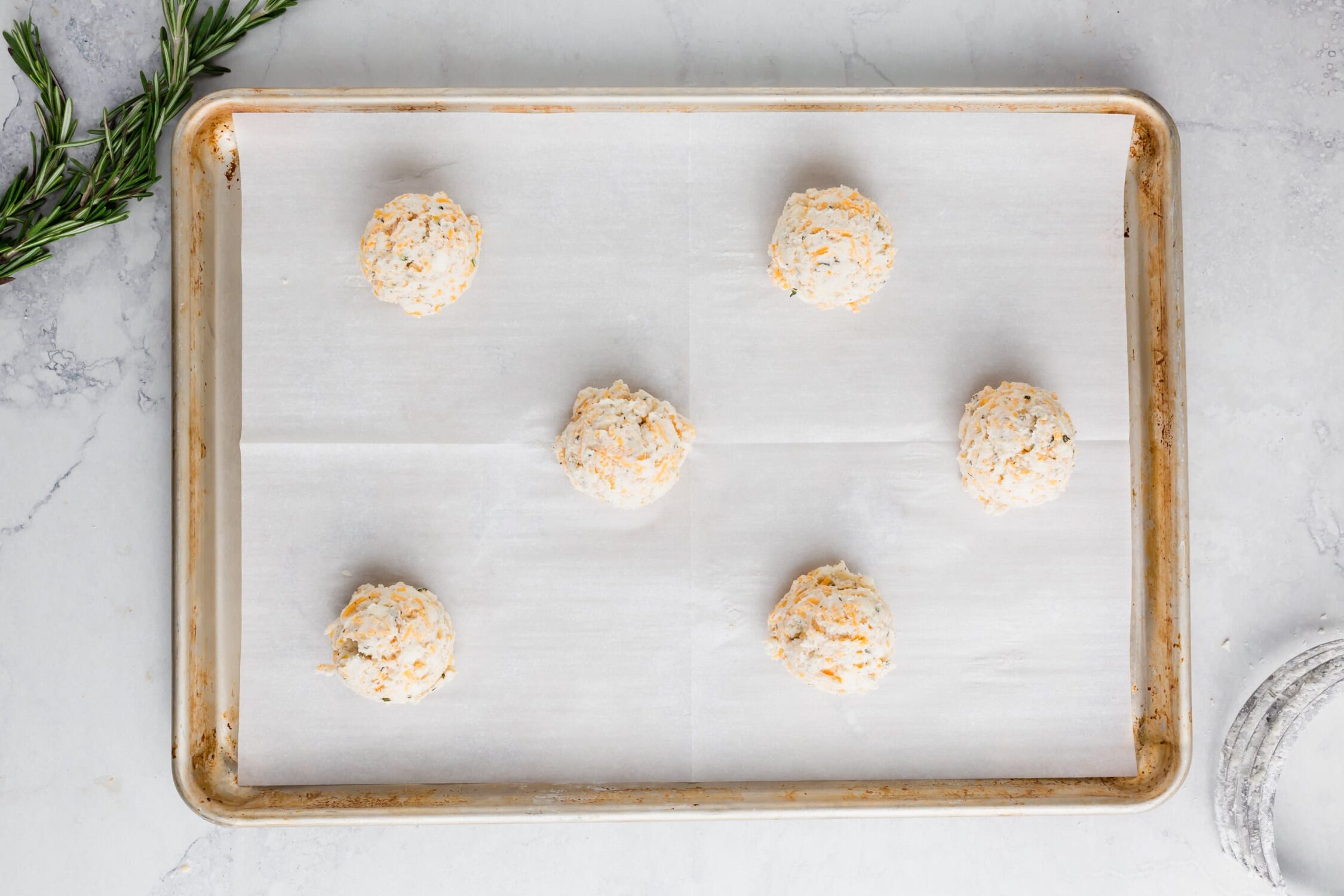 An overhead photo of gluten-free biscuit dough on a baking sheet ready to be baked.
