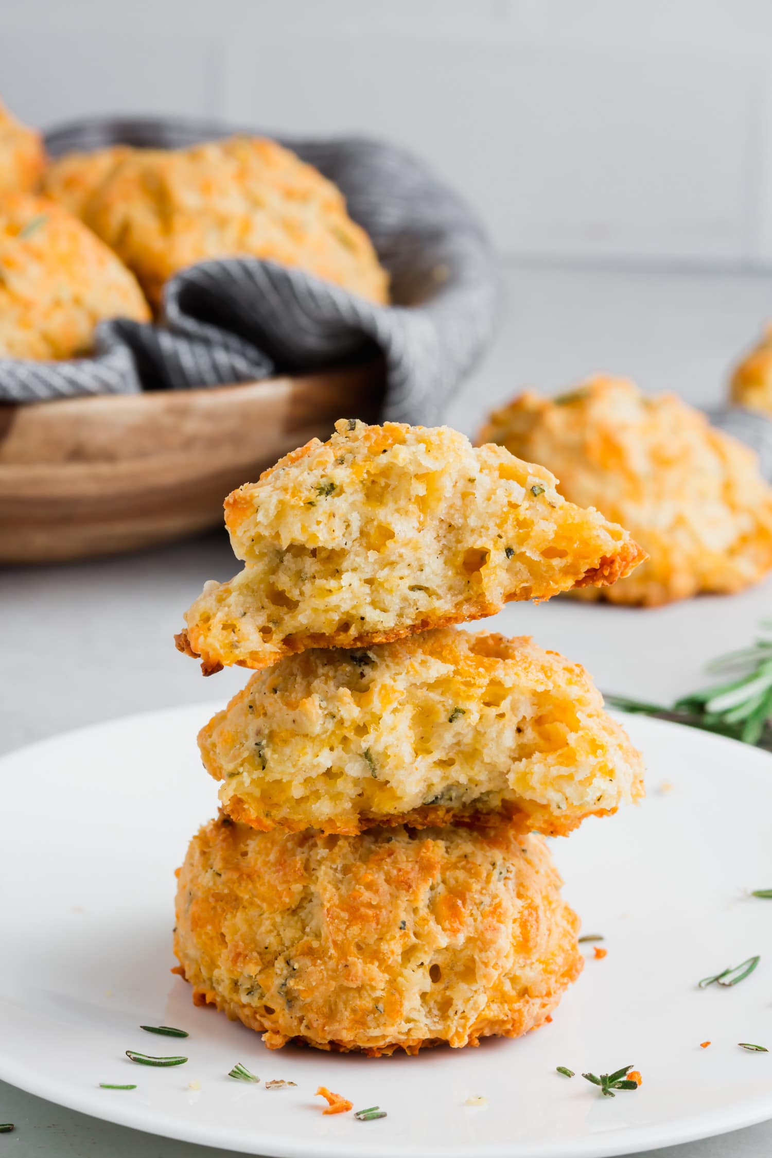 A photo of a stack of three cheddar biscuits with rosemary.