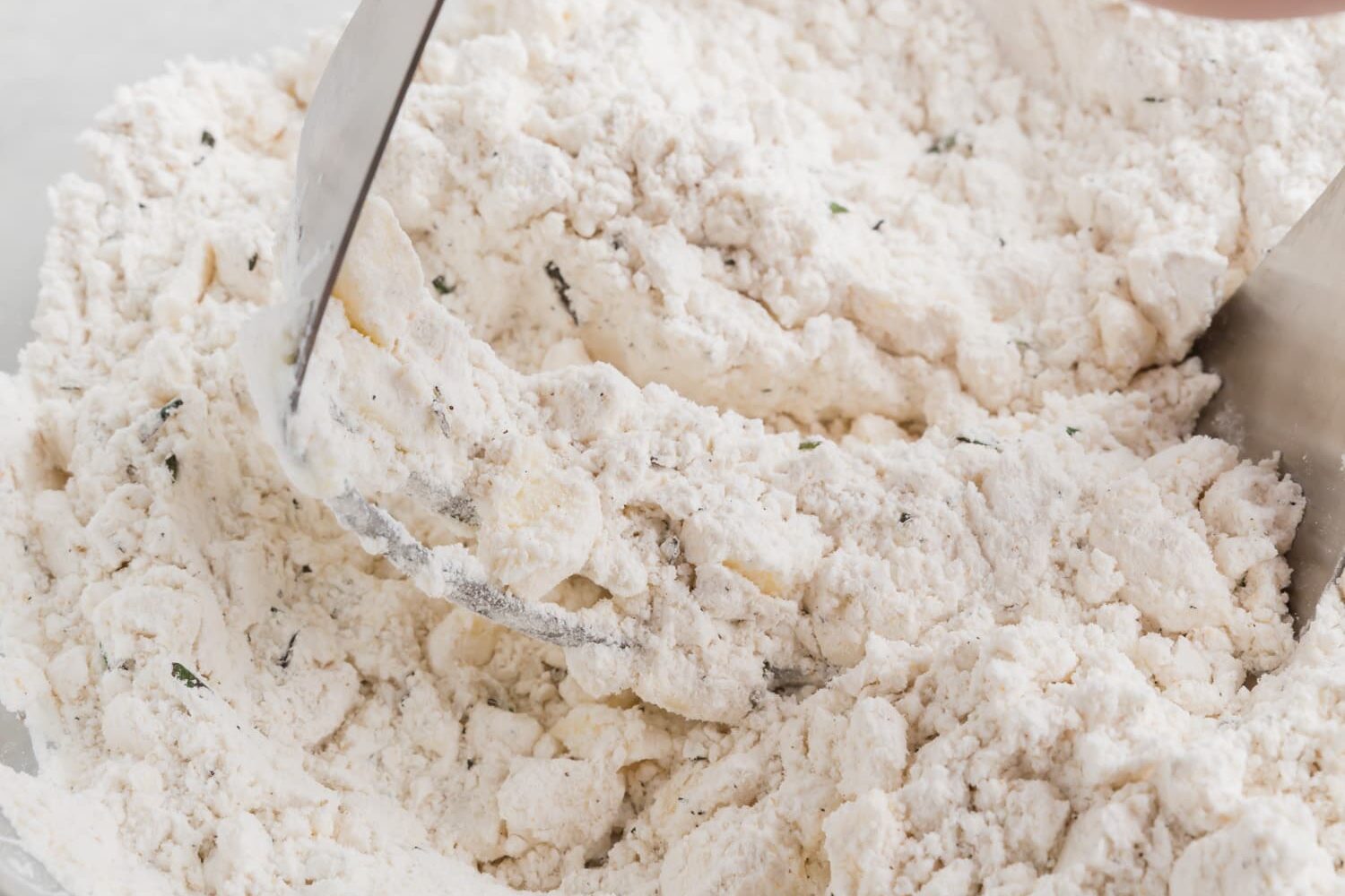 A photo of a pastry cutter cutting butter into gluten-free flour.