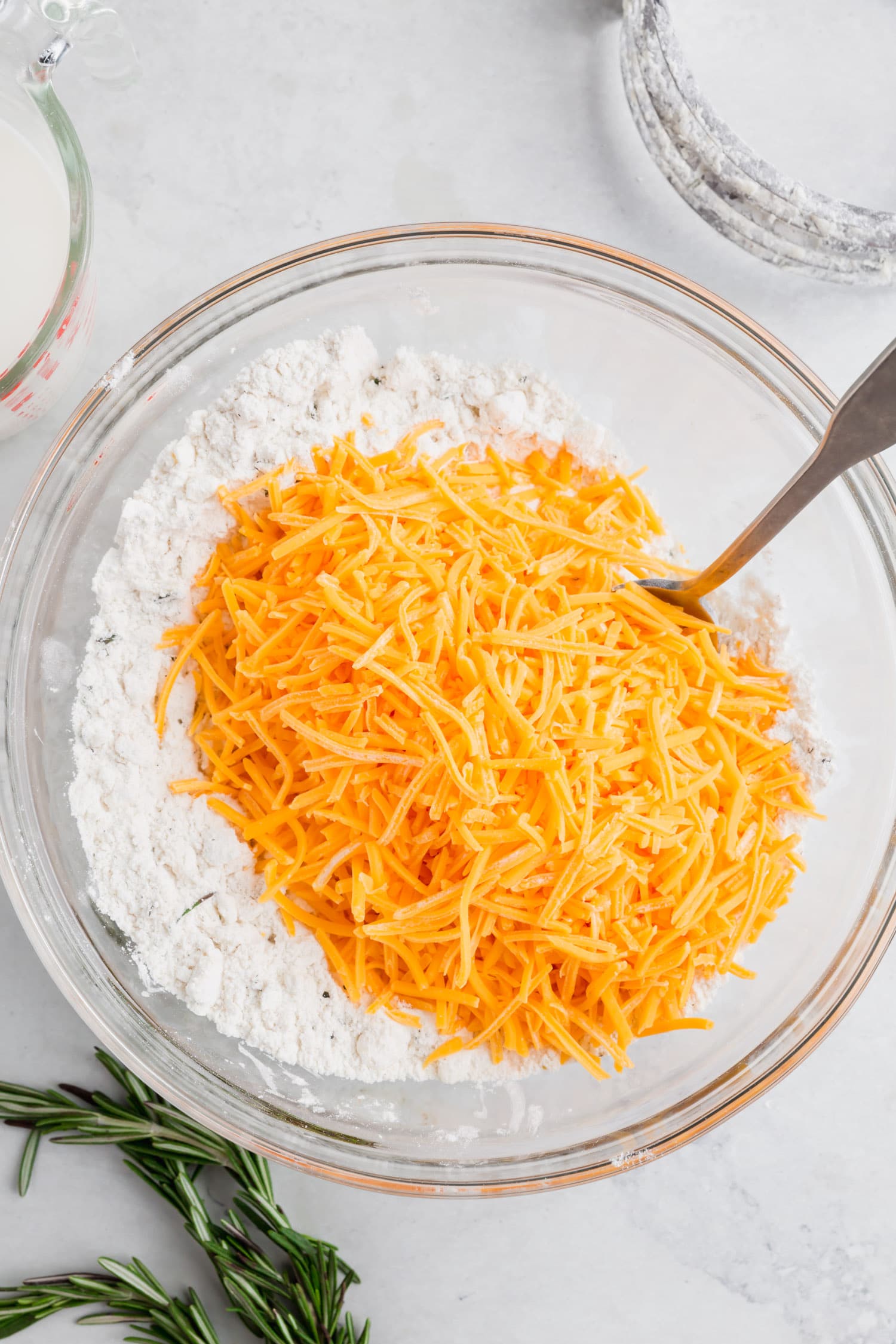 An overhead photo of a bowl of gluten-free flour with shredded cheddar cheese to make cheddar biscuits.