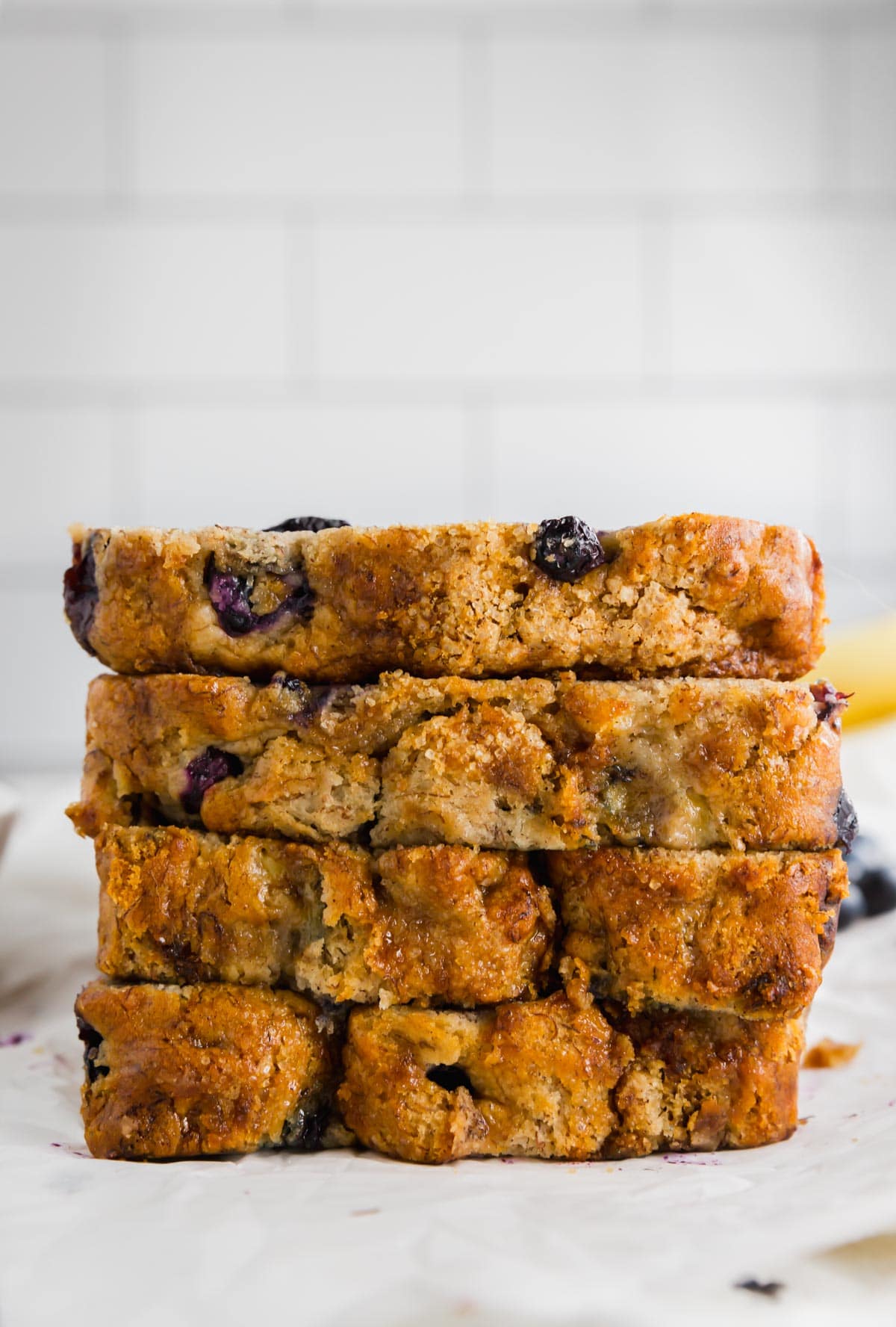 A photo of four slices of gluten-free blueberry banana bread stacked on top of each other.