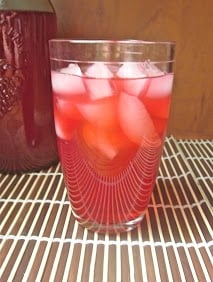 A glass of passion iced tea lemonade with ice cubes.