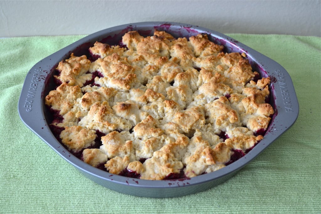 A cake pan with cherry cobbler on a green napkin.