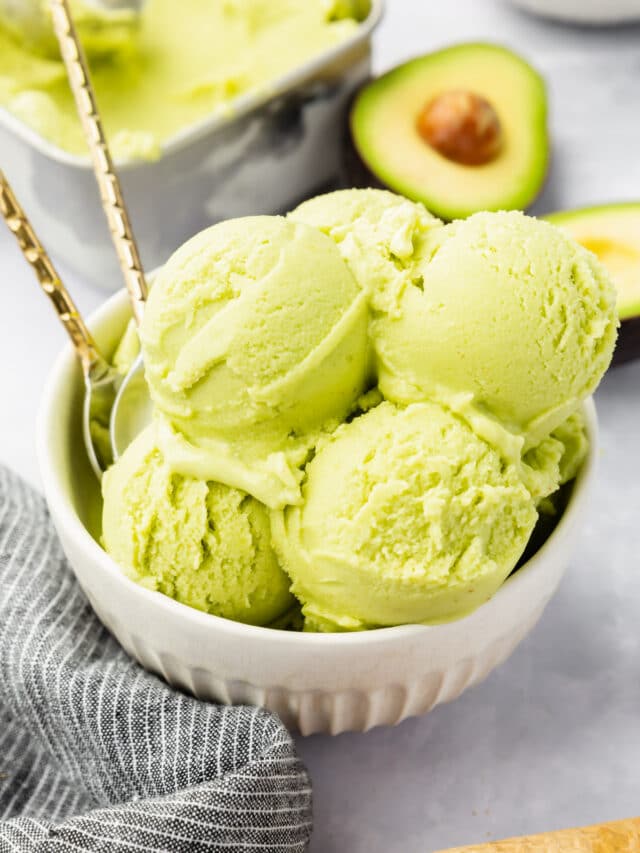 A bowl of avocado ice cream with avocados in the background.