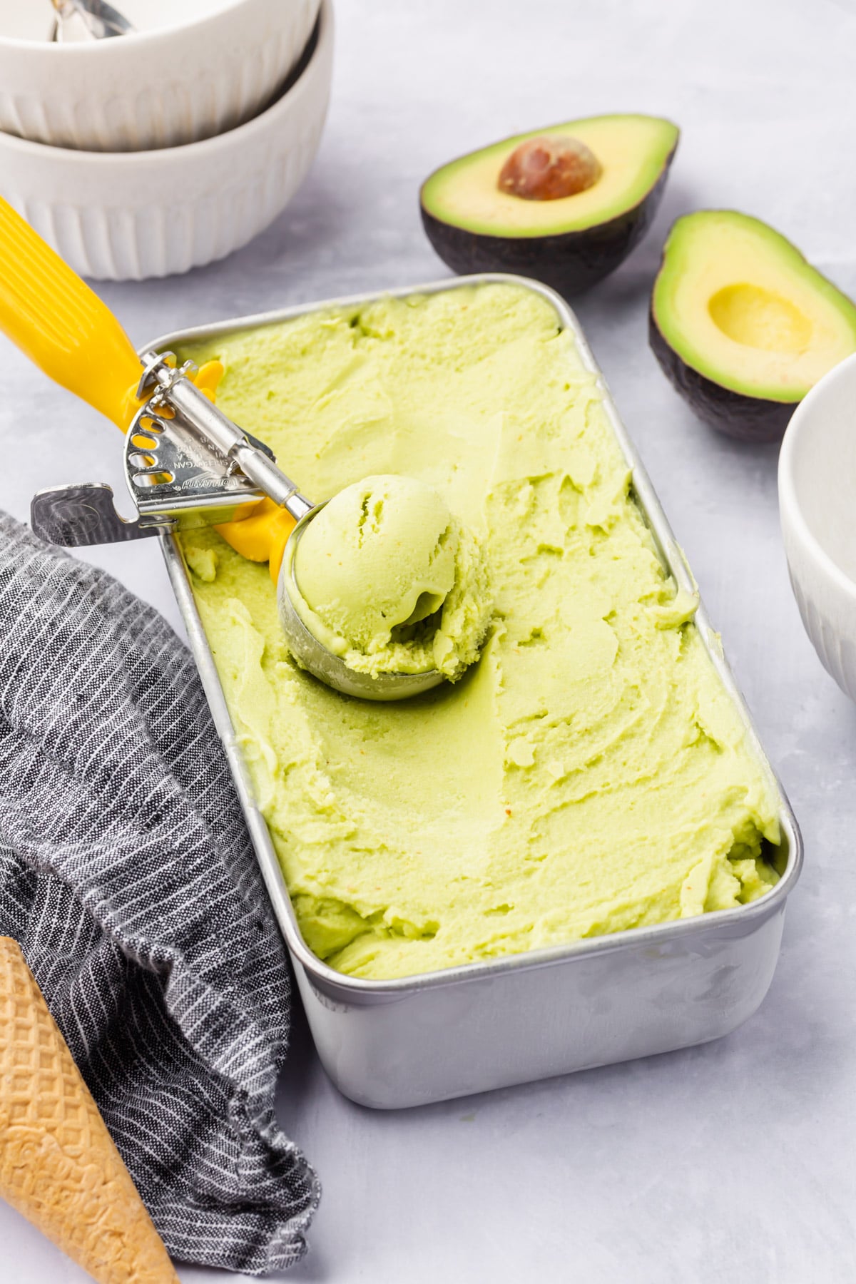 A loaf pan of avocado ice cream with a scooper in it. 