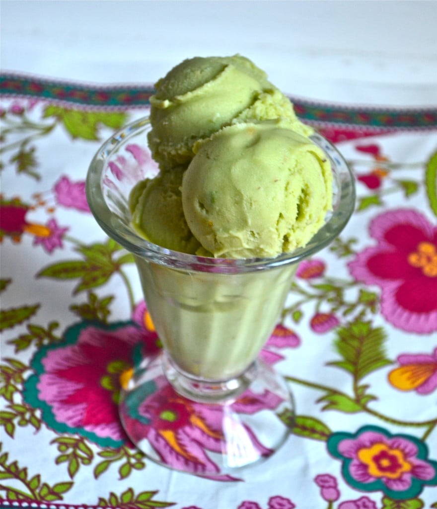 A fluted glass bowl of avocado ice cream on a floral napkin.
