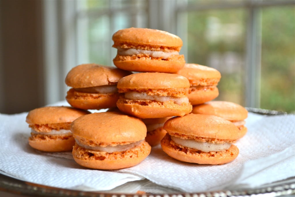 A stack of pumpkin pie macarons filled with cream cheese frosting.