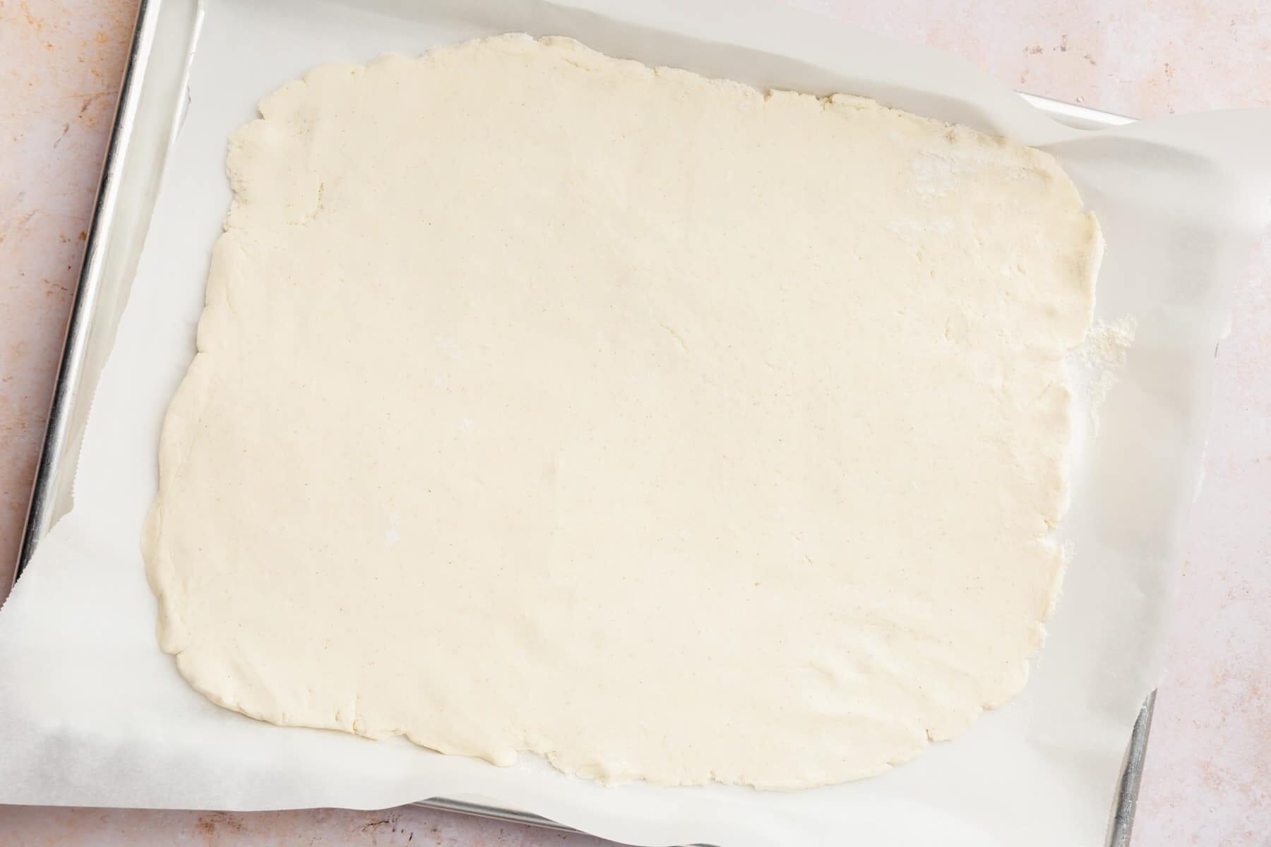 Gluten-free dough rolled out onto a baking sheet lined with parchment paper.