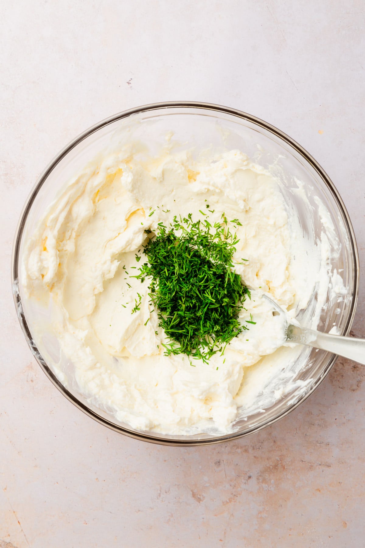 A bowl of softened cream cheese with fresh dill poured in the center.