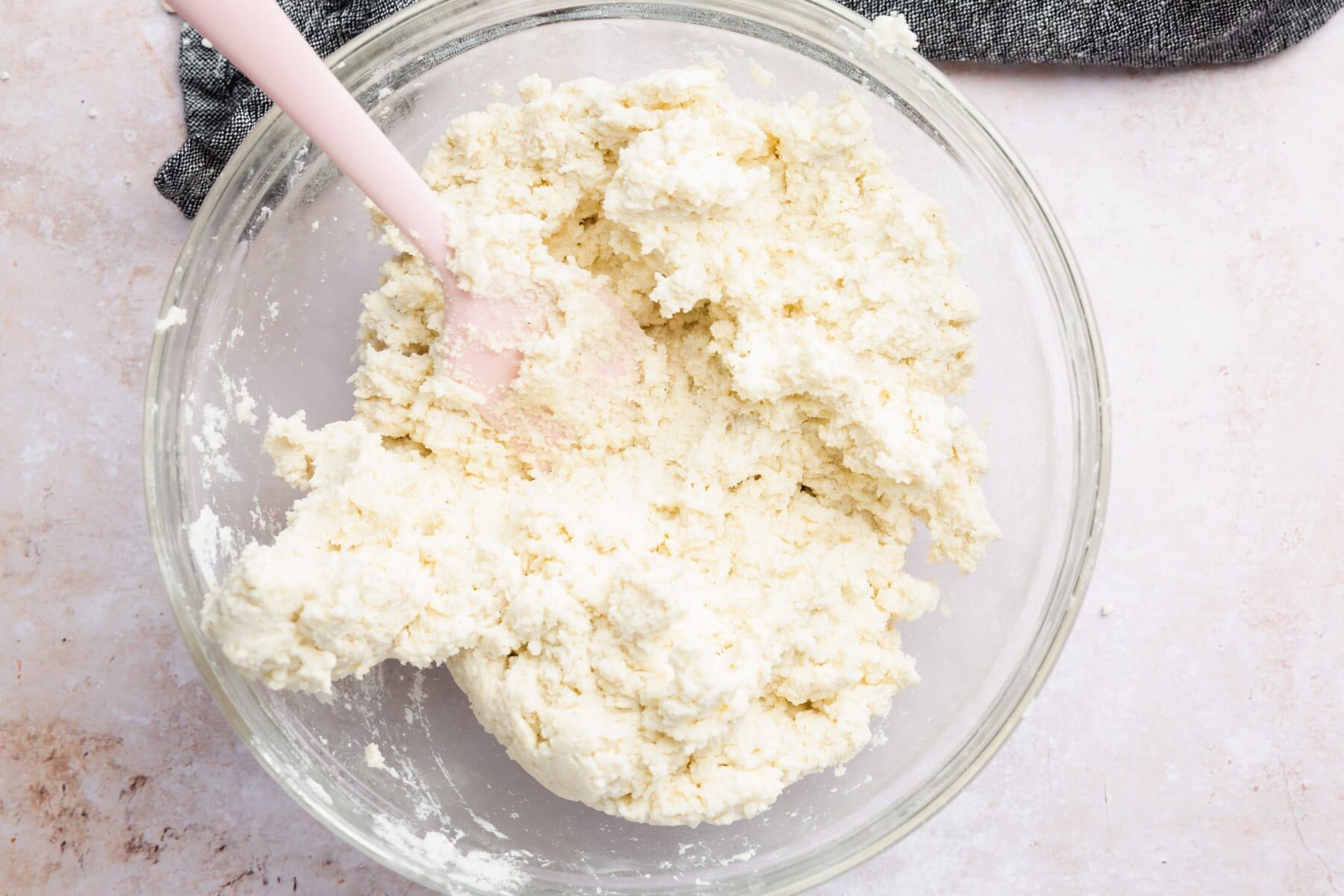 A bowl of gluten-free dough with a pink spatula.