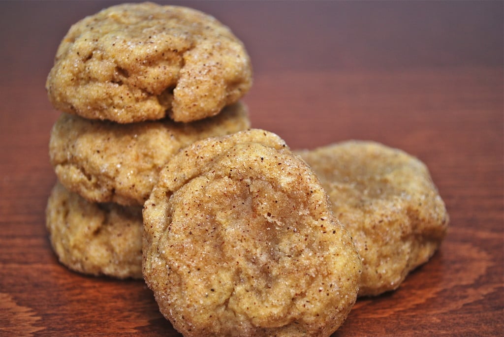 A stack of pumpkin snickerdoodle cookies with one cookie leaning against the stack.