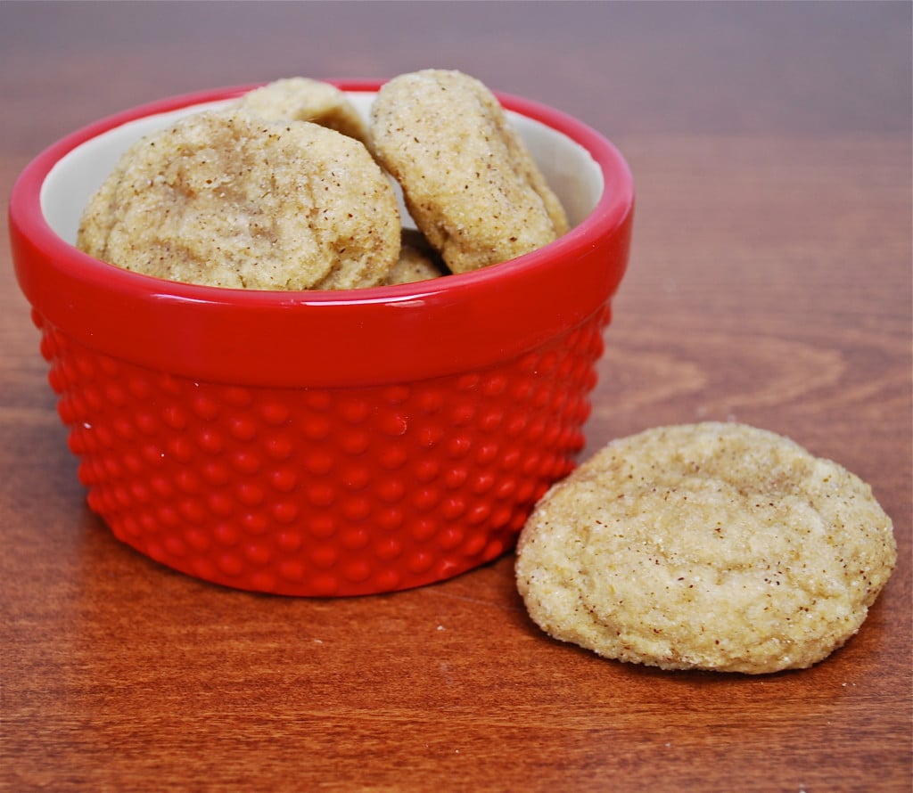 A pile of pumpkin snickerdoodle cookies in a red bowl with one cookie on the surface.