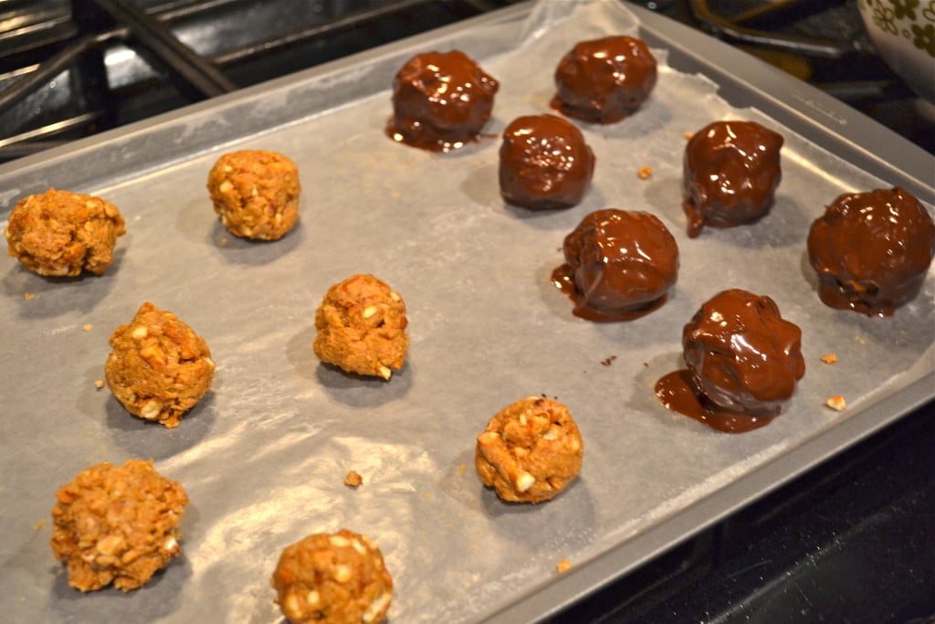 Peanut butter pretzel truffles on a baking sheet - half dipped in melted chocolate.