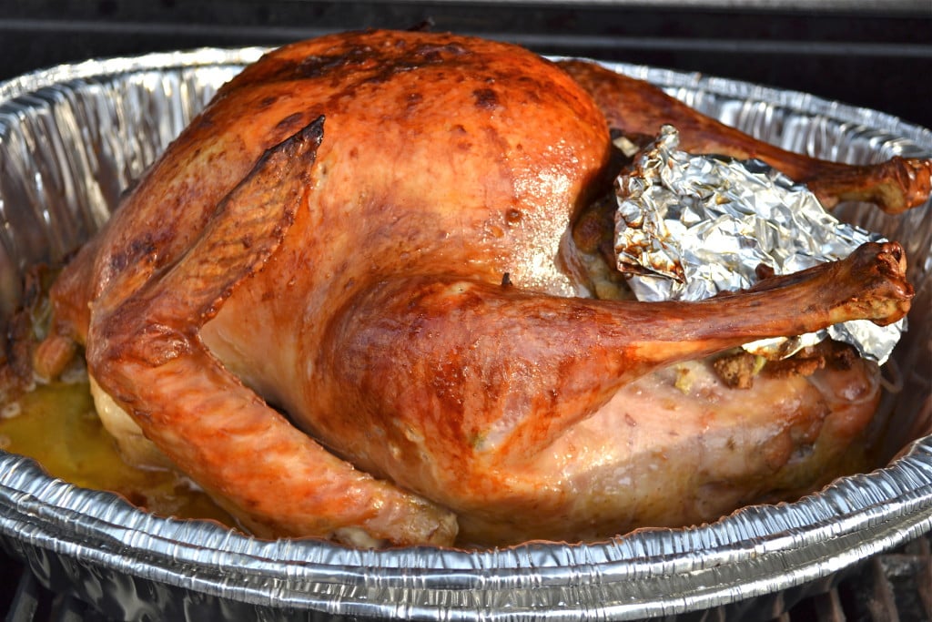 A grilled turkey in a aluminum pan.