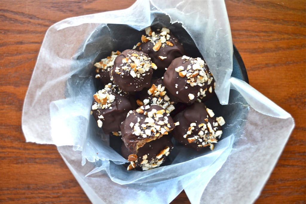 A bowl lined with parchment paper filled with chocolate pretzel truffles.