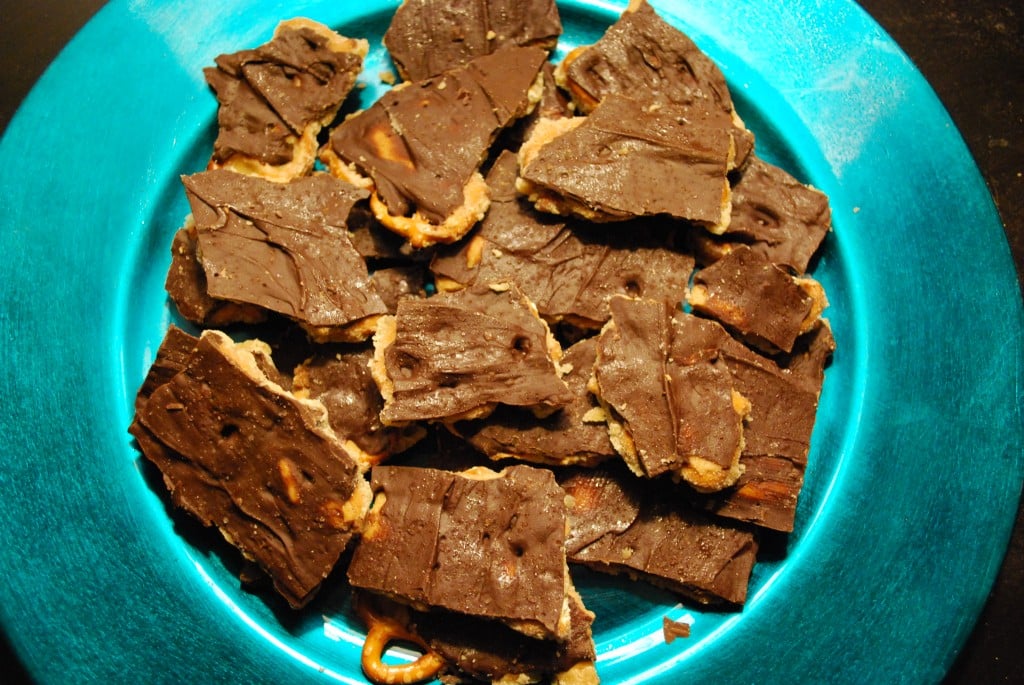 Salted caramel and chocolate pretzel bark on a turquoise platter.