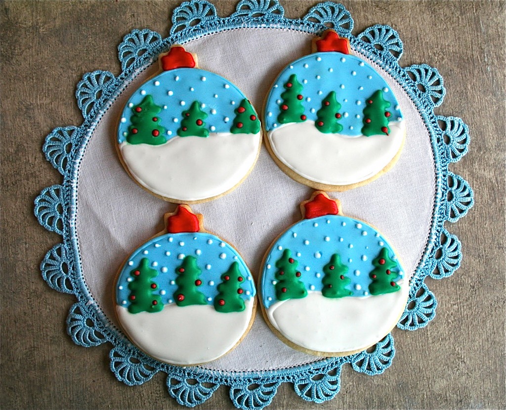 snow globe sugar cookies on a white and blue placemat.