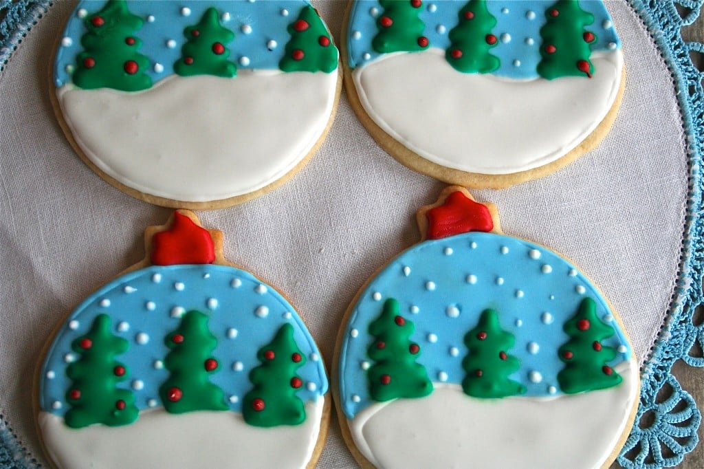 Snowglobe ornament Christmas trees on a white and blue placemat. 