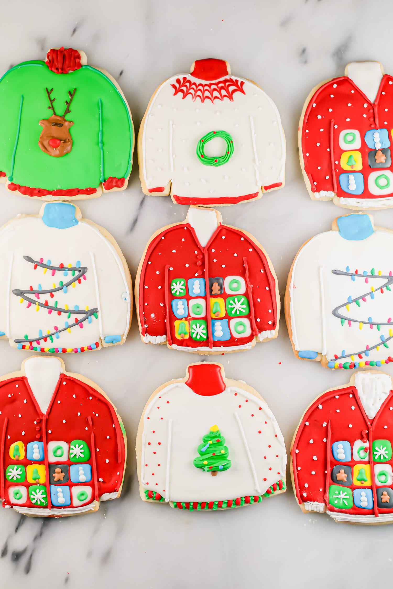 An overhead photo of rows of ugly sweater sugar cookies decorated with royal icing.