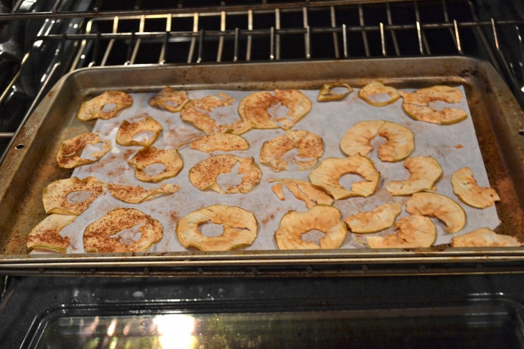 A baking sheet of baked apple with cinnamon in the oven.