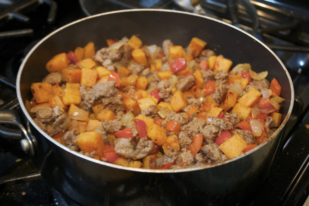 A skillet with sweet potato, ground turkey, and red bell pepper hash. 
