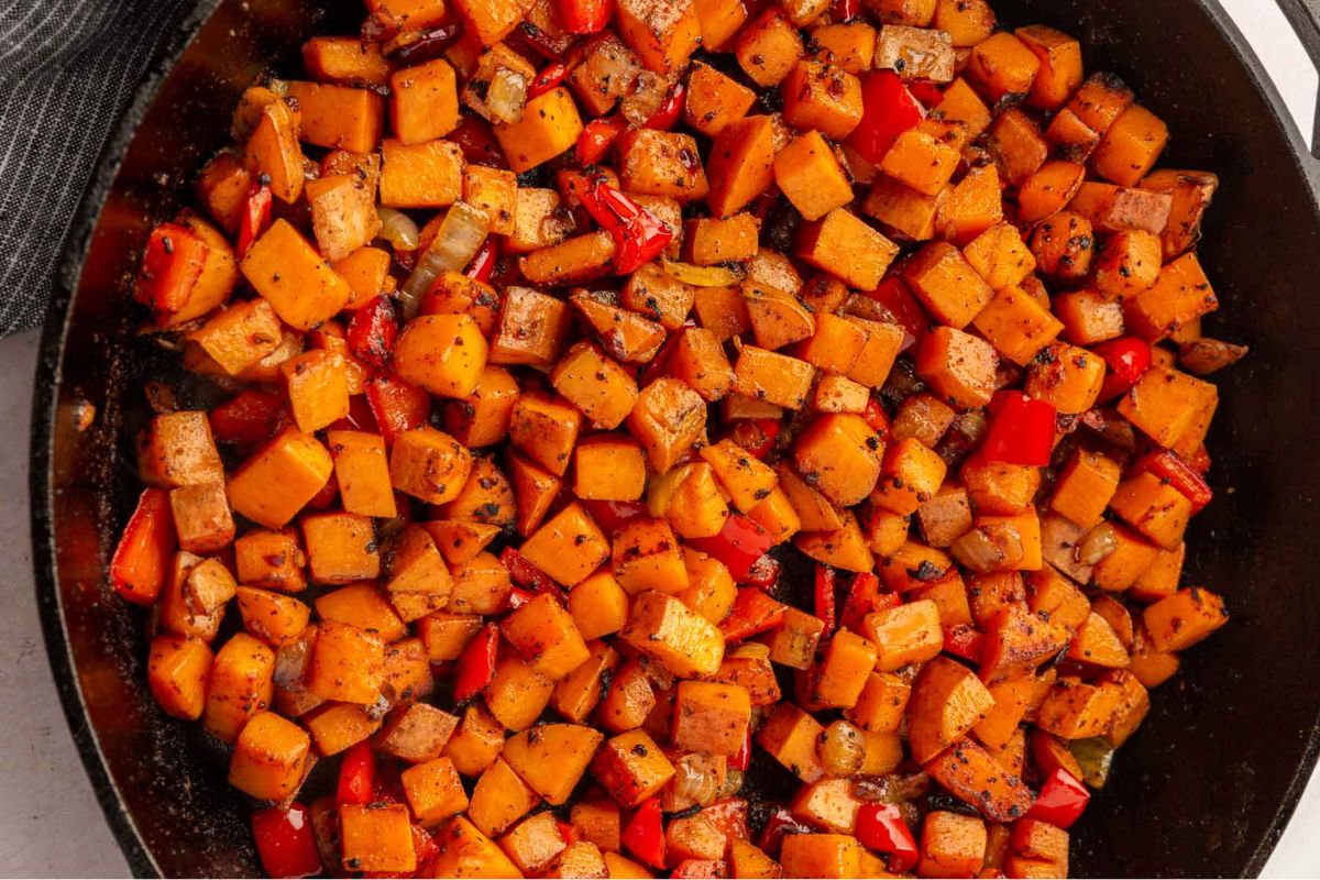 Tender sweet potatoes and bell peppers in a cast iron skillet.