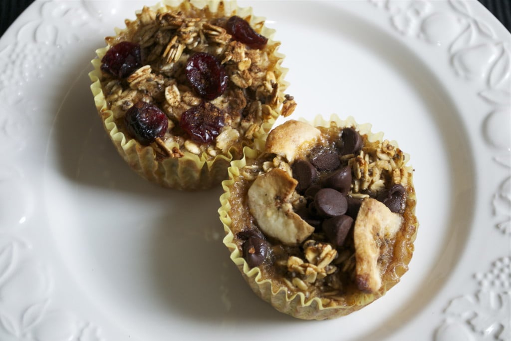 Two baked oatmeal cups topped with chocolate chips, banana chips, and dried cranberries. 