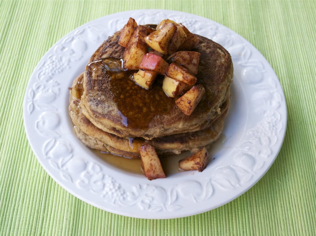 A stack of pancakes topped with sautéed apples and maple syrup. 
