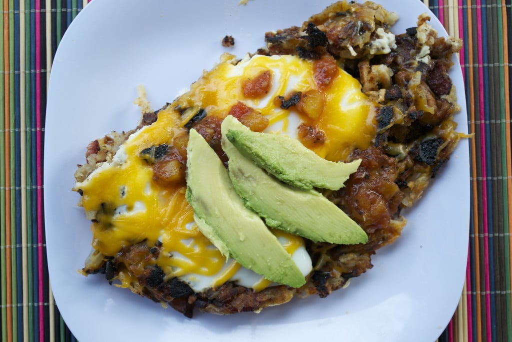 Hash Brown Egg Skillet topped with melted cheddar cheese, salsa and sliced avocado. 